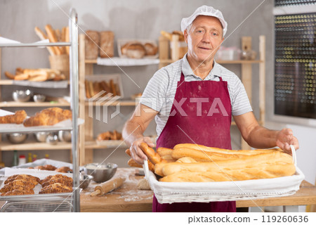 Elderly man baker with basket of baguettes 119260636