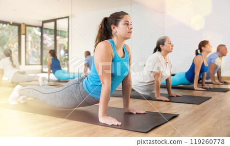 Group of young mature old people in sportswear exercising Pilates while stretching on mats in rehabilitation center 119260778