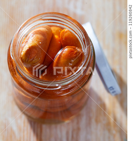 Tinned sausages in glass jar on a wooden table Tinned sausages in glass jar on a wooden table 119260842