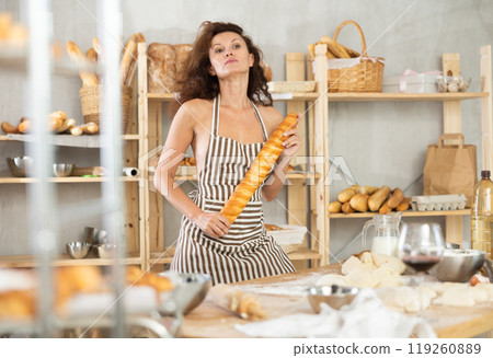 Woman in apron and chefs hat with loaf of bread and baguette in hands 119260889
