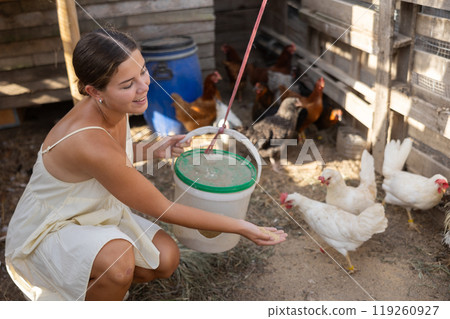 Young woman feeding chickens in henhouse 119260927