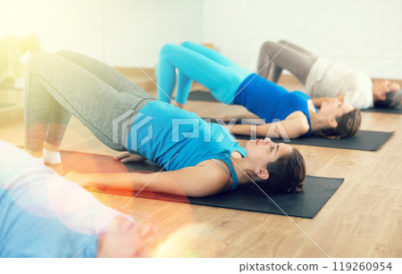 Young girl performing glute bridge during training Young girl performing glute bridge during training 119260954