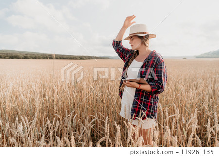 Young Woman Standing in a Wheat Field with a Tablet 119261135