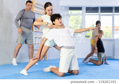 Boy and girl train to perform defense of strangling opponent, while learning self-defense 119261191