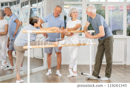 Active old attendees of ballet courses communicating cheerfully at ballet-barre 119261345