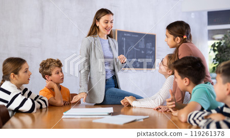 Teacher talking to group of preteen schoolchildren in classroom 119261378