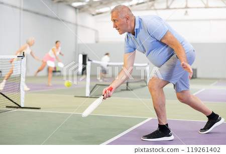 Active elderly pickleball player on tennis court Active elderly pickleball player on tennis court 119261402