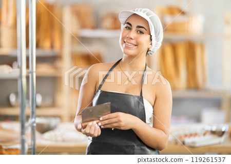 Young female baker with dough scraper Young female baker with dough scraper 119261537