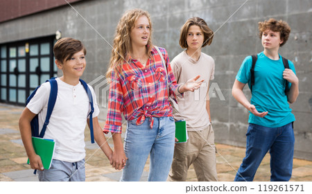 Four teenagers talking about play on walk in street Four teenagers talking about play on walk in street 119261571