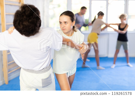 Group of children in sportswear exercising self protection techniques in pair during class at gym Group of children in sportswear exercising self protection techniques in pair during class at gym 119261578