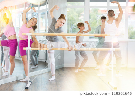 Ballet pose grand batman - girls and boys at a choreography lesson are learning ballet movements in studio Ballet pose grand batman - girls and boys at a choreography lesson are learning ballet movements in studio 119261646
