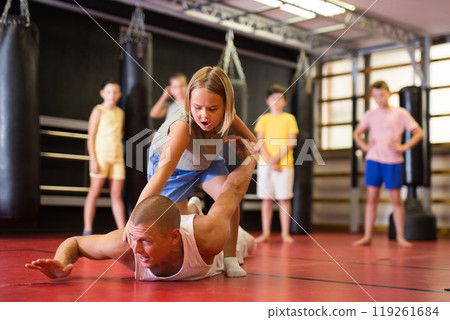 Girl in gym doing armlock move on trainer Girl in gym doing armlock move on trainer 119261684