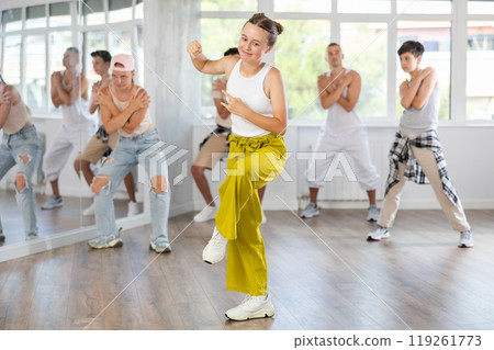 Teenage girl dancing hip-hop against background of group members Teenage girl dancing hip-hop against background of group members 119261773