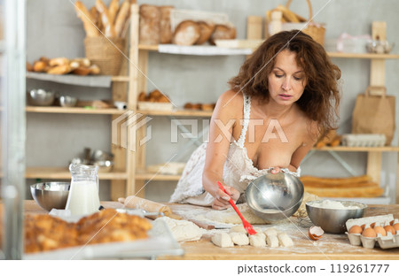 Woman whisking eggs and pouring batter on kitchen counter in bakery 119261777