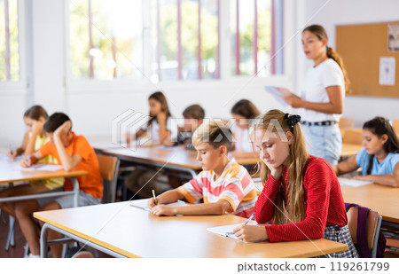 Preteen pupils studying in classroom with female teacher 119261799