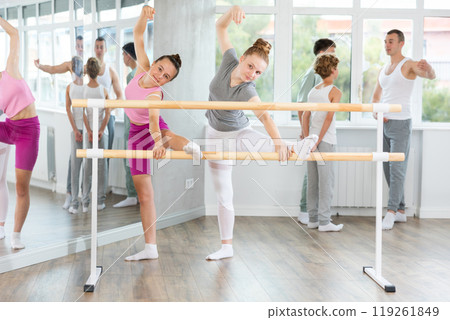 Ballet pose grand batman - girls and boys at a choreography lesson are learning ballet movements in studio Ballet pose grand batman - girls and boys at a choreography lesson are learning ballet movements in studio 119261849