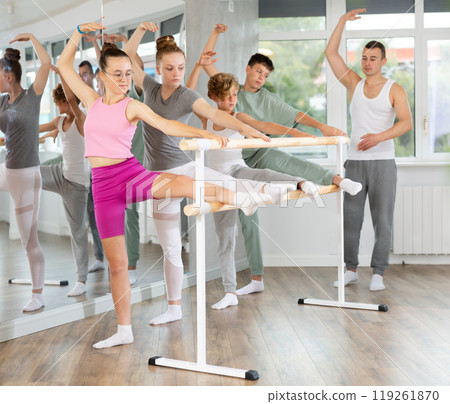 Teenage boys and girls practicing leg stretching exercise during ballet classes Teenage boys and girls practicing leg stretching exercise during ballet classes 119261870