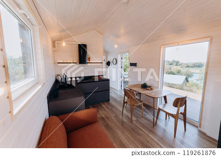 Modern open-concept kitchen and living area with natural light, cozy seating, and warm wooden design Modern open-concept kitchen and living area with natural light, cozy seating, and warm wooden design 119261876