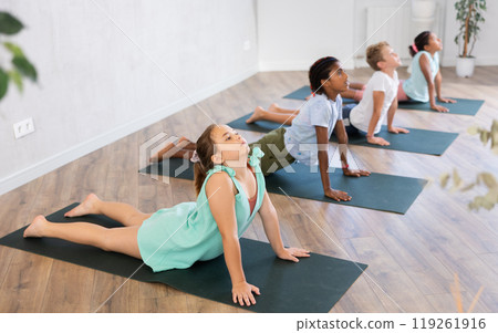 In sport studio with group of friends girl stand perform dog muzzle up, Urdhva Mukha Shvanasana In sport studio with group of friends girl stand perform dog muzzle up, Urdhva Mukha Shvanasana 119261916