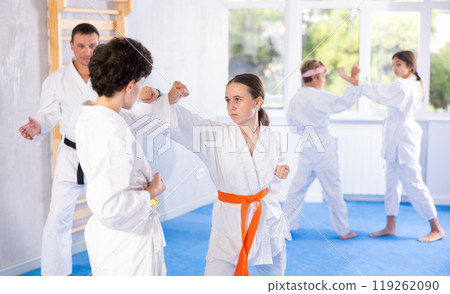 Girl and boy in pairs exercising karate movements during group training 119262090