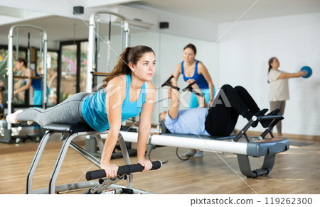Young girl doing exercises on wunda chair in pilates studio Young girl doing exercises on wunda chair in pilates studio 119262300