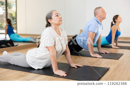 Elderly woman practicing pilates on mat in gym area Elderly woman practicing pilates on mat in gym area 119262366