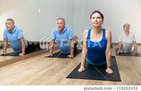 People of different ages performing cobra exercise during group Pilates workout. Active lifestyle and wellness concept 119262438