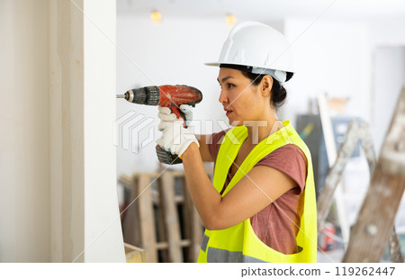 Asian woman construction worker drilling hole in wall 119262447