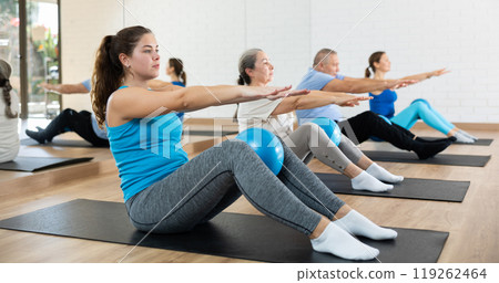 Young girl doing sit-ups with bender ball in pilates studio 119262464