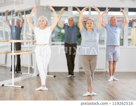 Confident senior woman training ballet moves with group of older people at ballet school Confident senior woman training ballet moves with group of older people at ballet school 119262518