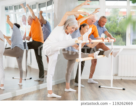 Ballet pose grand batman - elderly women and men at choreography lesson Ballet pose grand batman - elderly women and men at choreography lesson 119262669