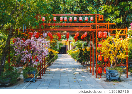 gate decorated with Chinese lanterns to a park with trees in a garden on Buddhist pagoda in Asia in Vietnam 119262716