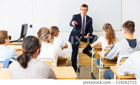 Male teacher lecturing to students at classroom Male teacher lecturing to students at classroom 119262723