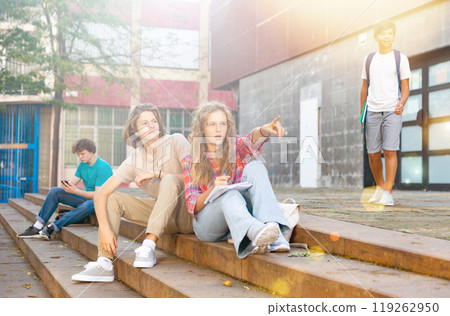 Teenagers sitting on stairs beside school Teenagers sitting on stairs beside school 119262950