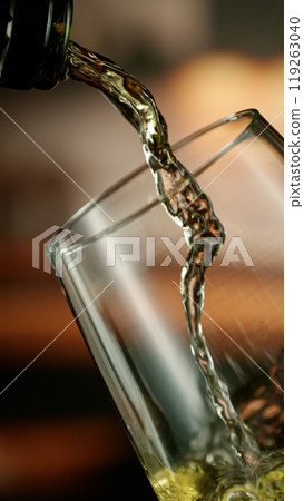Close-up of white wine pouring into glass , freeze motion. 119263040