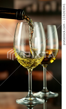 Close-up of white wine pouring into glass , freeze motion. 119263041