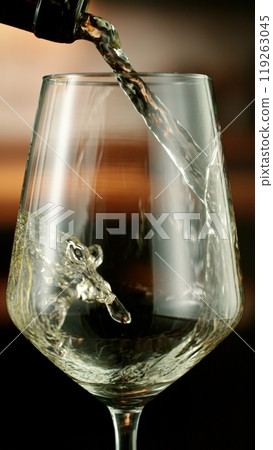 Close-up of white wine pouring into glass , freeze motion. 119263045