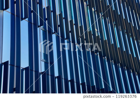 Close-up of modern glass building facade with geometric patterns reflecting sky. Contemporary architectural design. Close-up of modern glass building facade with geometric patterns reflecting sky. Contemporary architectural design. 119263376