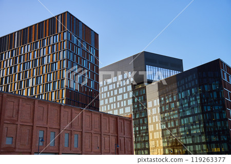 Modern glass office buildings reflecting city skyline in windows at sunset. Contemporary architectural design Modern glass office buildings reflecting city skyline in windows at sunset. Contemporary architectural design 119263377