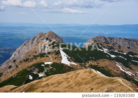 Rugged hiking trail leading to mountain summit with large cross under cloudy sky. Tatra mountains in Zakopane, Poland. Giewont mountain summit. Natural landscape Rugged hiking trail leading to mountain summit with large cross under cloudy sky. Tatra mountains in Zakopane, Poland. Giewont mountain summit. Natural landscape 119263380