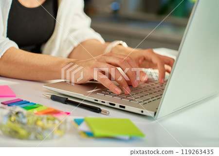 Woman working from home office typing on laptop keyboard with colorful sticky notes and stationery on desk Woman working from home office typing on laptop keyboard with colorful sticky notes and stationery on desk 119263435