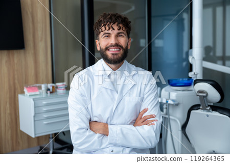 Bearded dentist man smiling while standing in dental clinic Bearded dentist man smiling while standing in dental clinic 119264365