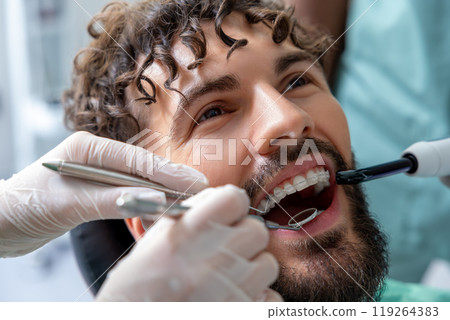 Patient in dental chair receiving oral examination or professional treatment from skilled dentist 119264383