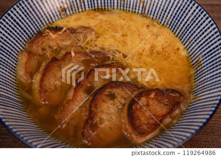 Classic French onion soup baked with cheese croutons sprinkled with fresh thyme, close up view. Classic French onion soup baked with cheese croutons sprinkled with fresh thyme, close up view. 119264986