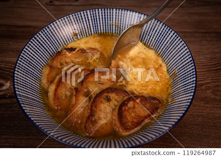 Classic French onion soup baked with cheese croutons sprinkled with fresh thyme, close up view. Classic French onion soup baked with cheese croutons sprinkled with fresh thyme, close up view. 119264987