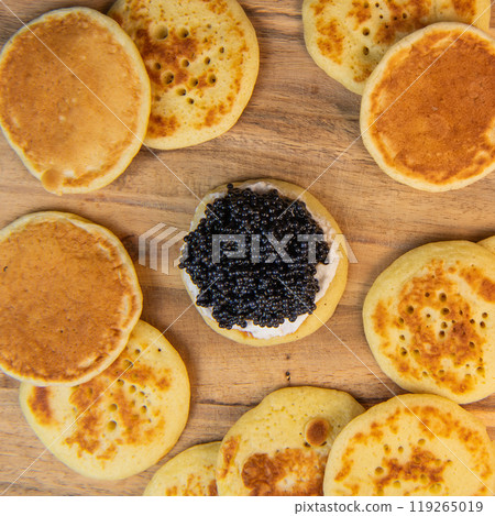 Blinis with black caviar and cream cheese, on a festive dish, mini pancakes, an elegant appetizer Blinis with black caviar and cream cheese, on a festive dish, mini pancakes, an elegant appetizer 119265019