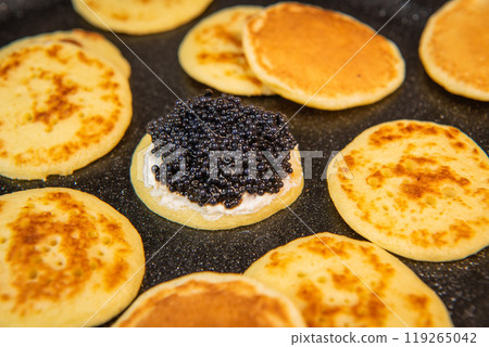 Blinis with black caviar and cream cheese, on a festive dish, mini pancakes, an elegant appetizer 119265042