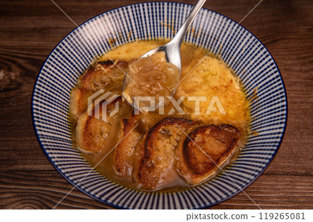 Classic French onion soup baked with cheese croutons sprinkled with fresh thyme, close up view. 119265081
