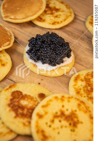 Blinis with black caviar and cream cheese, on a festive dish, mini pancakes, an elegant appetizer Blinis with black caviar and cream cheese, on a festive dish, mini pancakes, an elegant appetizer 119265087