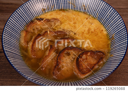 Classic French onion soup baked with cheese croutons sprinkled with fresh thyme, close up view. Classic French onion soup baked with cheese croutons sprinkled with fresh thyme, close up view. 119265088
